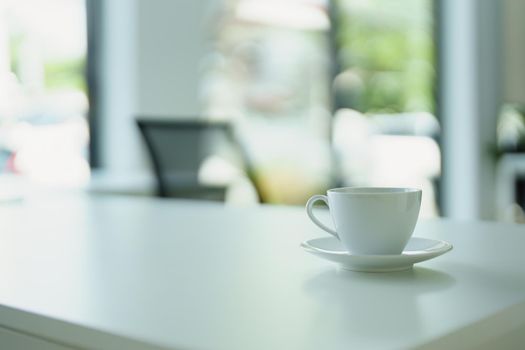 A cup of hot coffee is ready to drink on the desk.