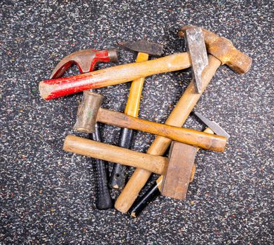 assortment of different old and used hammers on a dark colorful background.