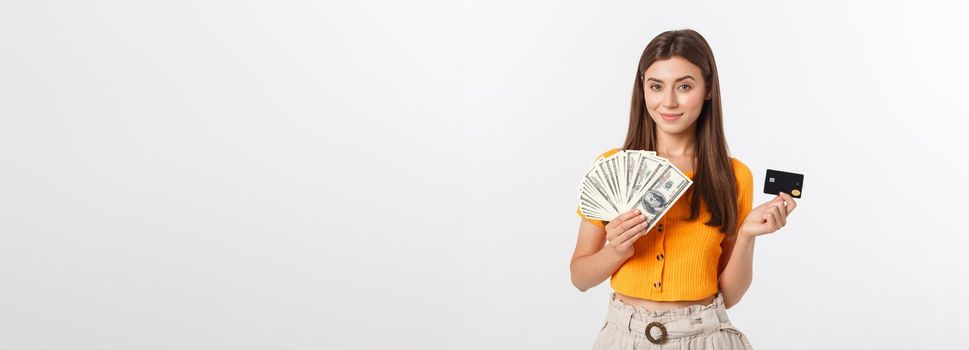 Photo of happy young woman standing isolated over grey background. Looking aside holding money and credit card.