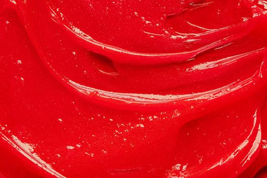 Red gel texture. Cosmetic clear liquid cream smudge. Skin care product sample closeup. Toothpaste or wax background