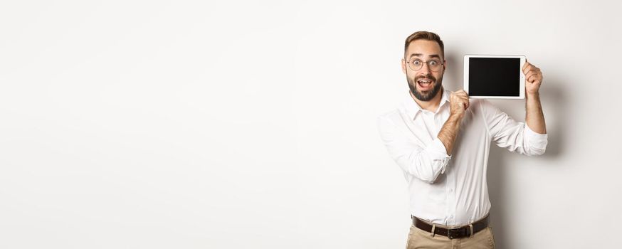 Shopping and technology. Handsome man showing digital tablet screen, wearing glasses with white collar shirt, studio background.