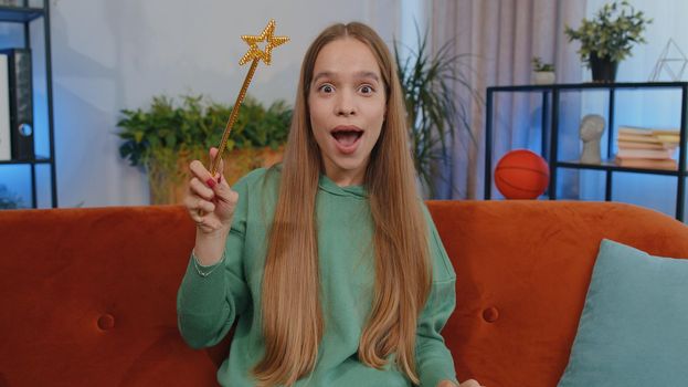 Portrait of student girl child kid magician wizard gesturing with magic wand fairy stick, making wish come true, casting magician spell, advertising holidays sale discount. Young woman at home room