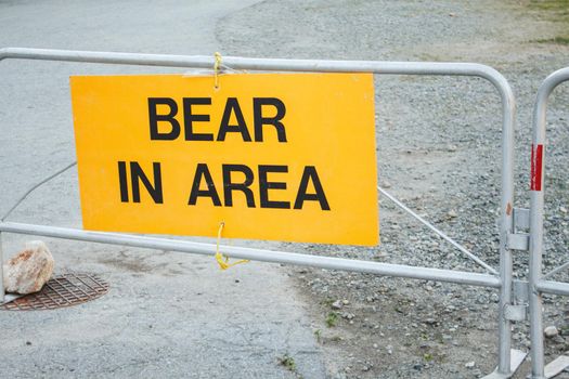 Yellow colored warning sign Bear In Area informing about wildlife activity in the area near trail in Provincial Park