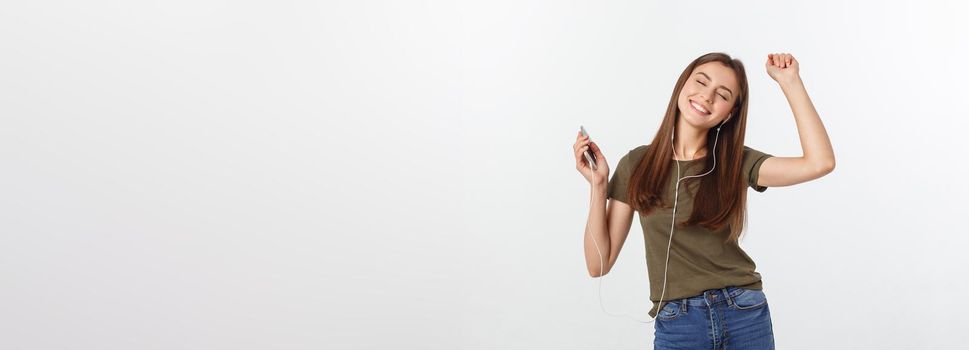 Portrait of a cheerful cute woman listening music in headphones and dancing isolated on a white background