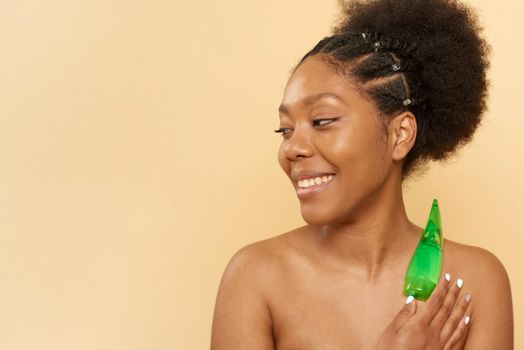 Beautiful woman with perfect skin holding aloe vera gel. Portrait of a beautiful African American woman with fresh skin. Skin care, moisturizing. Skin care product