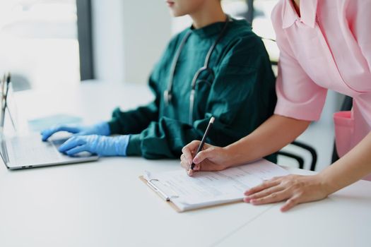 Portrait of Asian doctors and nurses using computers and documents to view patient information to analyze symptoms before treatment