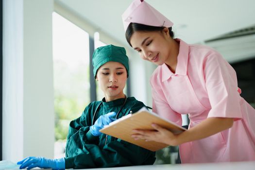 Portrait of Asian doctors and nurses using computers and documents to view patient information to analyze symptoms before treatment