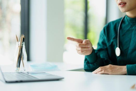 Portrait of an Asian doctor using a computer to look at patient data to analyze symptoms before treatment.