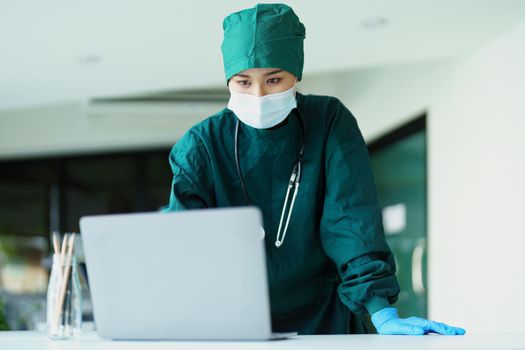 Portrait of an Asian doctor using a computer to look at patient data to analyze symptoms before treatment.