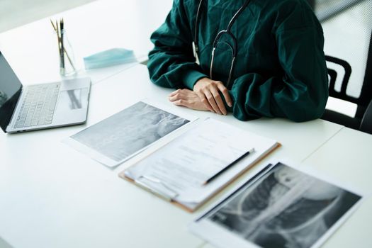 Portrait of an Asian doctor looking at patient X-ray film to analyze the abnormality of the client's body.