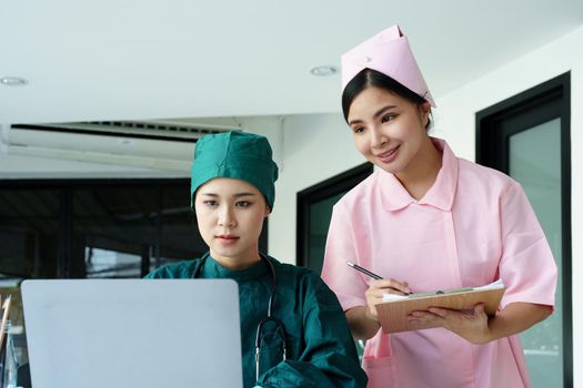 Portrait of Asian doctors and nurses using computers and documents to view patient information to analyze symptoms before treatment