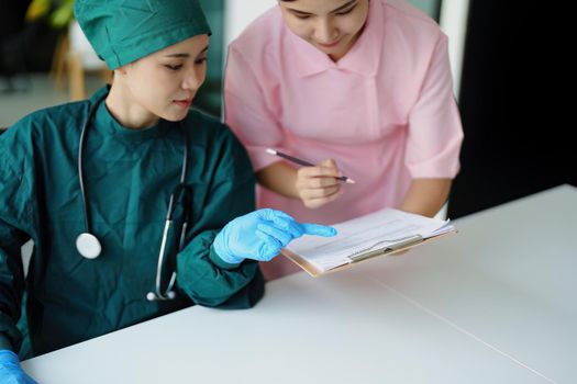 Portrait of Asian doctors and nurses using computers and documents to view patient information to analyze symptoms before treatment