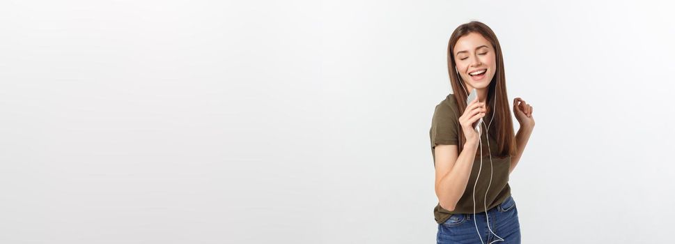 Portrait of a cheerful cute woman listening music in headphones and dancing isolated on a white background