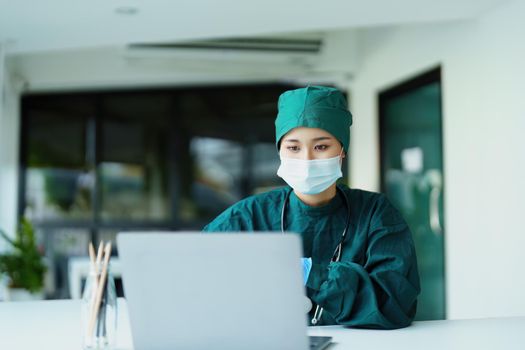 Portrait of an Asian doctor using a computer to look at patient data to analyze symptoms before treatment.