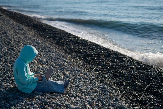 Caucasian woman working freelance on laptop on the beach