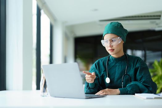 Portrait of an Asian doctor using a computer to look at patient data to analyze symptoms before treatment.