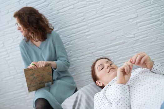 A middle-aged woman lies on a couch and talks to a psychologist