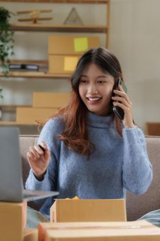 Asian SME business woman talking with client by phone at home office. online shopping concept.