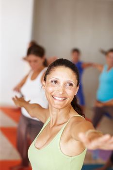 The warrior pose. A young woman doing a balancing yoga stretch in yoga class