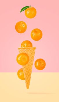 Isolated ice cream cone with fruits in the air. Seven falling whole tangerines on colored background with clipping path as package design element and advertising. Full depth of field.