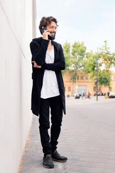smiling young man with beard talking happy on mobile phone, concept of urban lifestyle and technology of communication, copy space for text