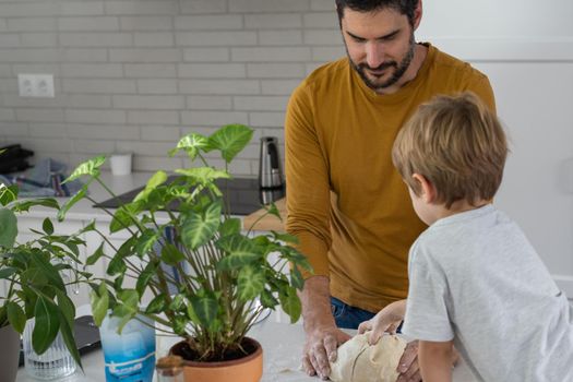 young man making homemade bread with his son in his home kitchen