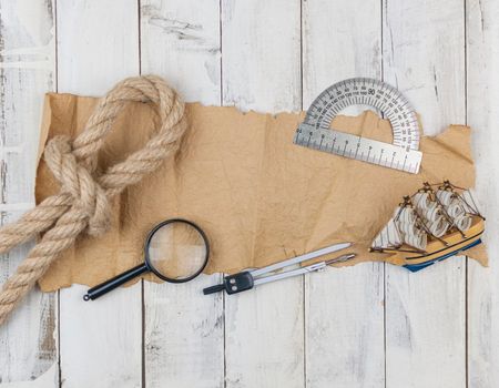 old paper, rope, magnifying glass and model classic boat on wood background 