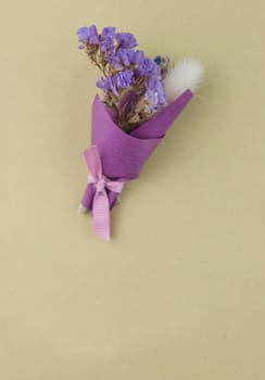 A bouquet of dried wild flowers with gift postcard on a white textured background made of antique wooden boards horizontal view from above