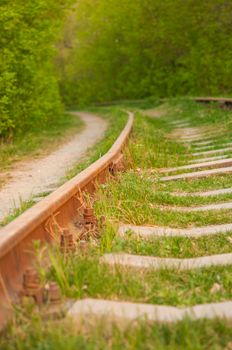 Abandoned railroad with rusty rails in the forest. Concept of crisis in transportation