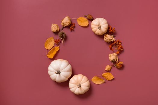 Autumn flat lay wreath of pumpkin, leaves and flowers with berries top view with copy space.
