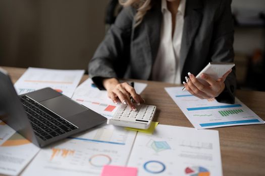 Accountant woman working on desk using calculator for calculate finance report in office.