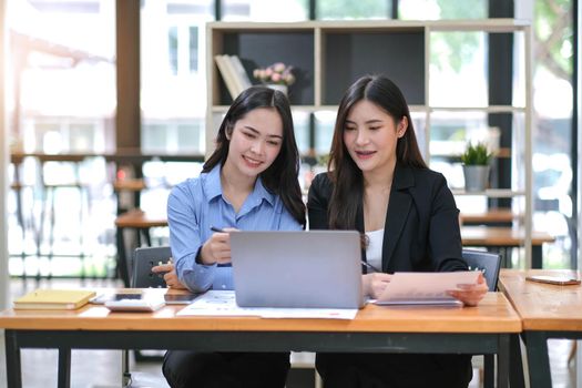 Two Young Asian businesswoman discuss with new startup project Idea presentation, analyze planning and financial statistics and investment market at office..