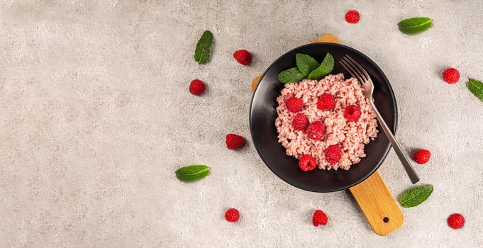 Healthy food on gray concrete background. Fresh raspberries risotto on a delicate and elegant dish