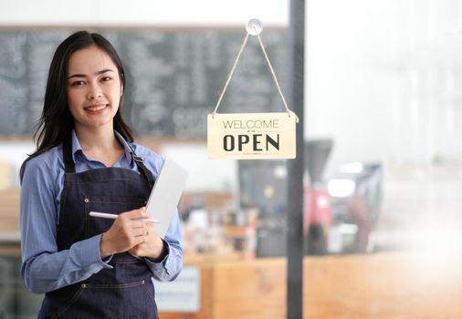Startup successful small business owner sme beauty girl stand with tablet smartphone in coffee shop restaurant. Portrait of asian tan woman barista cafe owner. SME entrepreneur seller business concept.