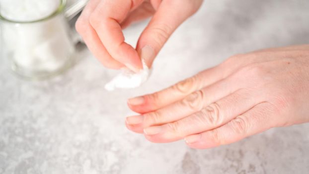 Woman finishing her manicure at home with simple manicure tools. Removing old nail polish from the nails.