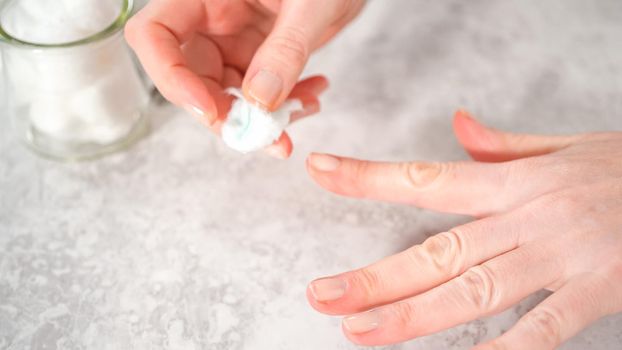 Woman finishing her manicure at home with simple manicure tools. Removing old nail polish from the nails.