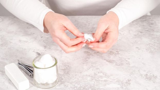 Woman finishing her manicure at home with simple manicure tools. Removing old nail polish from the nails.