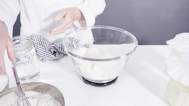 Measuring ingredients into a glass bowl to bake cinnamon rolls.