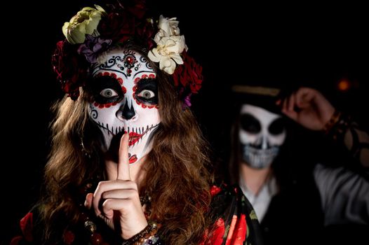 Woman in santa muerte costume and man in skeleton bodypainting for halloween