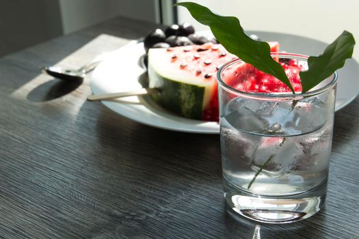 Summer snack. Fresh berries and fruits on a wooden table with green leaves of plants.