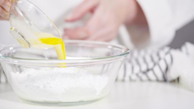 Mixing ingredients in a glass bowl to prepare glace for homemade cinnamon rolls.