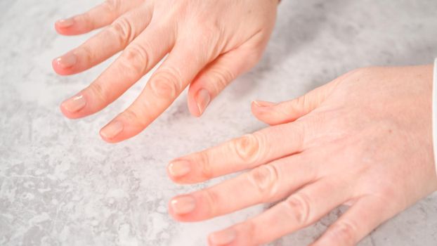 Woman finishing her manicure at home with simple manicure tools. Painting nails with fresh nail polish.