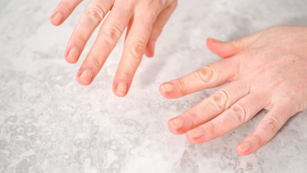 Woman finishing her manicure at home with simple manicure tools. Painting nails with fresh nail polish.