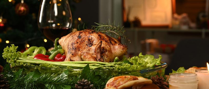Thanksgiving table or Christmas dinner roasted turkey, glass of red wine all sides dishes in decorated room with a Christmas tree.