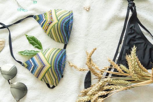 A bikini swimsuit and sunglasses on a white towel with spikelets of ripe wheat.,,