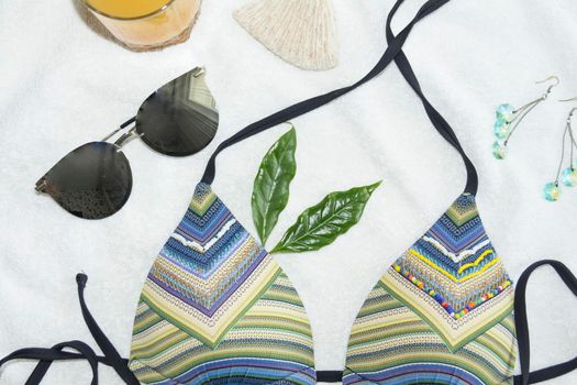 A bikini swimsuit, rhinestone earrings and sunglasses on a white towel.,,
