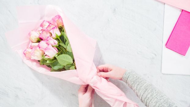 Flat lay. Step by step. Florist arranging a bouquet from pink roses.