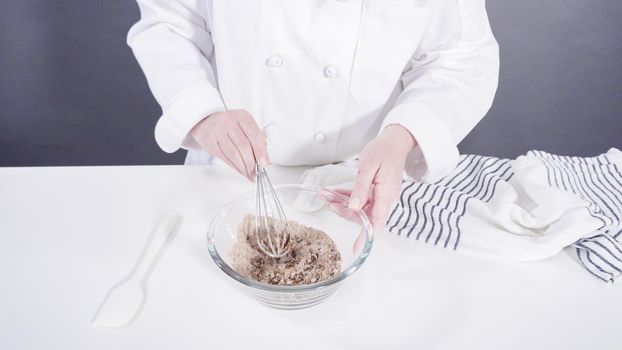 Mixing ingredients in a glass bowl to prepare glace for homemade cinnamon rolls.