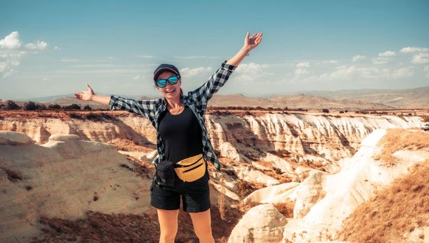 Tourist standing with raised hands on canyon in Cappadocia background, Turkey