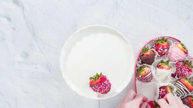 Flat lay. Step by step. Placing chocolate dipped strawberries on a white cake stand.